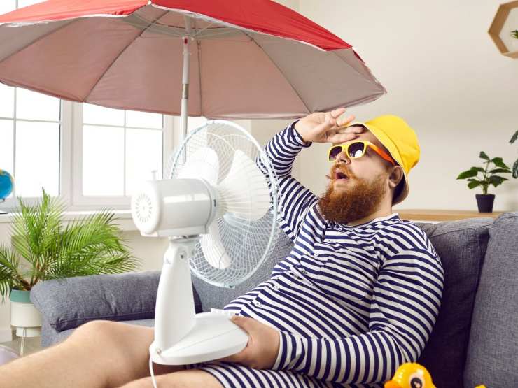 uomo davanti al ventilatore ed ombrellone