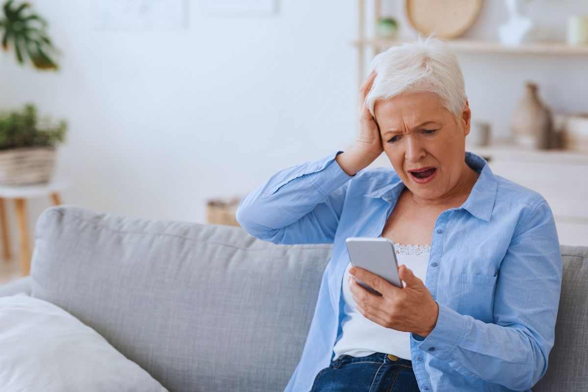Donna anziana preoccupata guarda lo smartphone