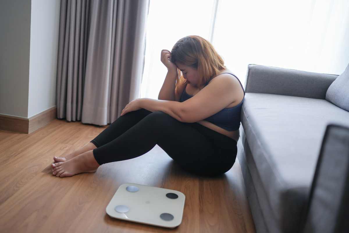 Donna triste seduta vicino alla bilancia