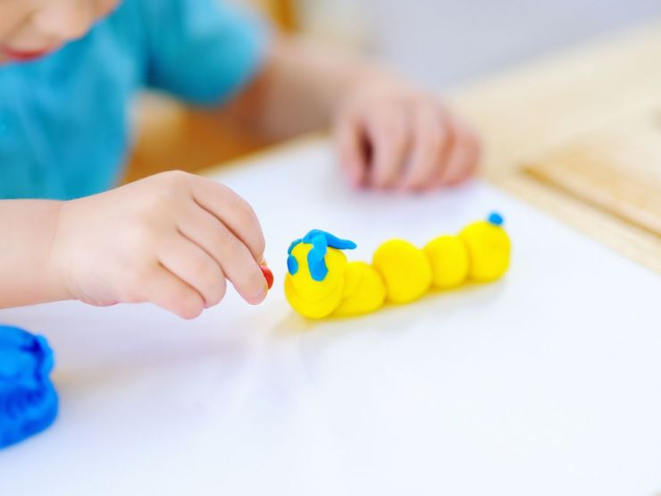 Bambino che realizza verme con pasta modellabile
