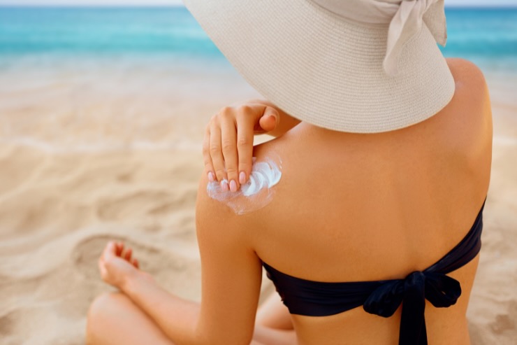donna di spalle che mette crema solare