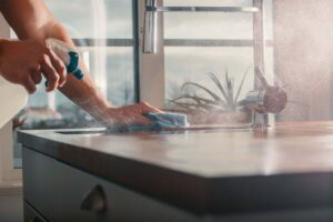 Mano pulisce piano da lavoro cucina con detersivo spray e panno