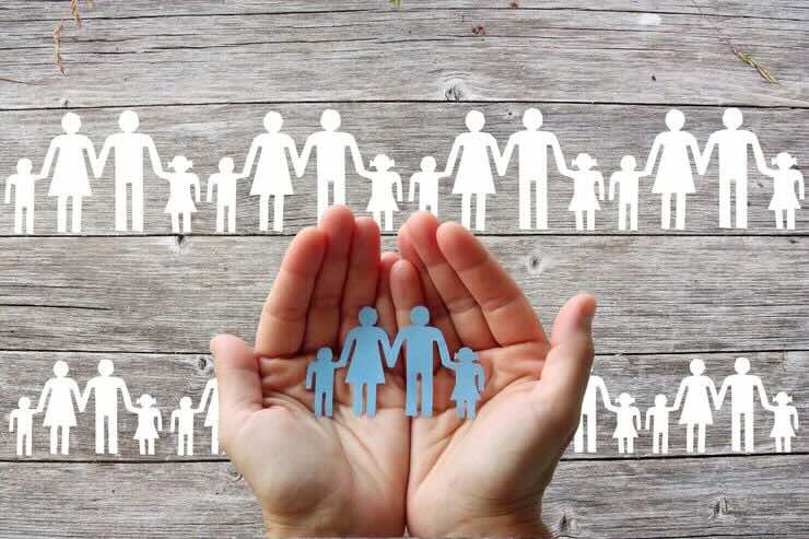 Mani con famiglia fatta con omini di carta, mamma, papà, due bambini