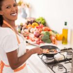 Donna cuoce qualcosa in padella, sorridente