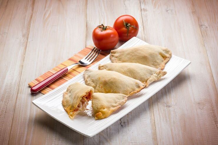 Fagottini ripieni su tagliare, pomodori, forchetta