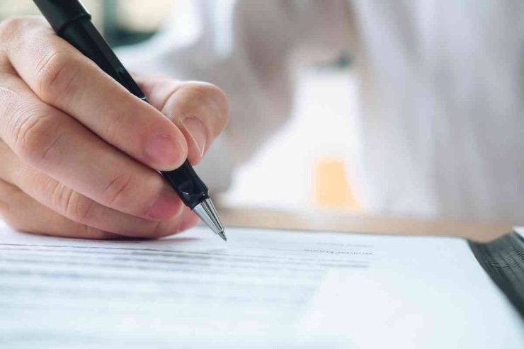 persona con penna che firma un foglio