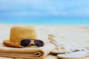 Cappello occhiali e stuoia poggiati sulla spiaggia
